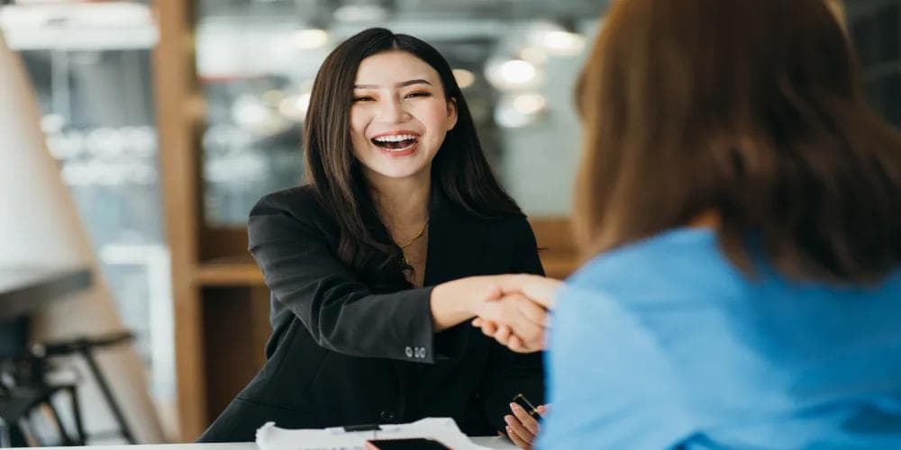 Smiling businesswoman shaking hands at a meeting, symbolising career planning, professional success, and guidance through Bazi analysis.